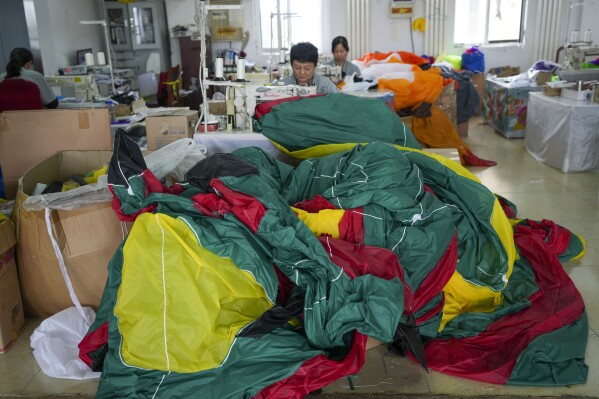 Workers stitch kites at a workshop in Weifang, Shandong Province of China, Friday, April 19, 2024. (AP Photo/Tatan Syuflana)