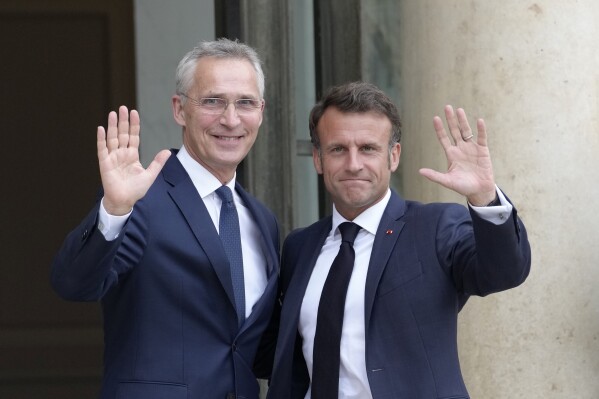 French President Emmanuel Macron, right, and NATO Secretary General Jens Stoltenberg wave before their talks Wednesday, June 28, 2023 at the Elysee Palace in Paris. NATO Secretary-General Jens Stoltenberg said earlier that he has called a meeting of senior officials from Turkey, Sweden and Finland on July 6 to try to overcome Turkish objections to Sweden joining the military organization. (AP Photo/Christophe Ena)