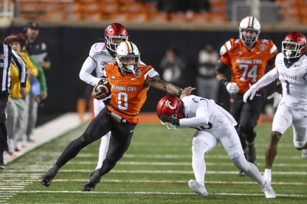 Cincinnati's Bryon Threats moves in to tackle Oklahoma State's Ollie Gordon II (0) during the first half of an NCAA college football game Saturday, Oct. 28, 2023, in Stillwater, Okla. (AP Photo/Mitch Alcala)