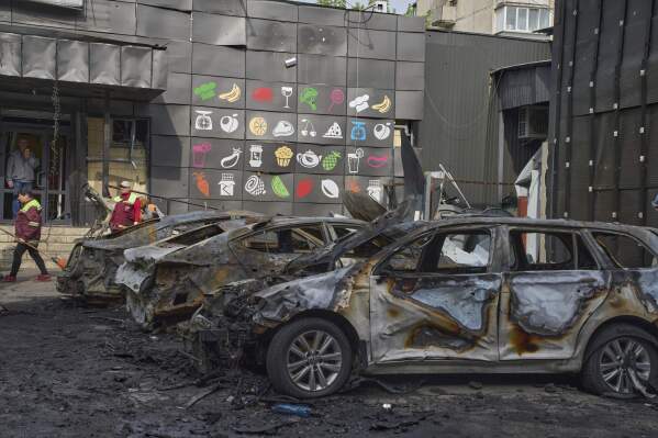 Municipal workers clean up near burnt cars in the residential area following Russia's drone attack in Kyiv, Ukraine, Sunday, May 4, 2025. (AP Photo/Efrem Lukatsky)
