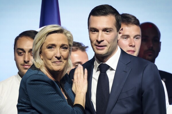 FILE - Leader of the French far-right National Rally Marine Le Pen, left, and lead candidate of the party for the upcoming European election Jordan Bardella during a political meeting on June 2, 2024 in Paris. At just 28 years old, Jordan Bardella has led the French far right to a landslide victory in the European Parliament election in June. After voters propelled Marine Le Pen's National Rally to a strong lead in the first round of national legislative elections on Sunday, Bardella has turned to rallying supporters to grant Marine Le Pen's party an absolute majority in the decisive round of voting on July 7 and make him the prime minister of France. (AP Photo/Thomas Padilla, File)