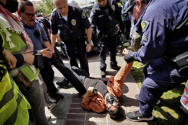 A University of Southern California protester is arrested by USC Department of Public Safety officers during a pro-Palestinian occupation at the campus' Alumni Park, Wednesday, April 24, 2024 in Los Angeles.  (AP Photo/Richard Vogel)
