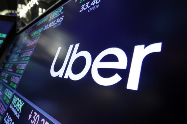 FILE - The Uber logo appears above a trading post on the floor of the New York Stock Exchange, Aug. 16, 2019. Uber posted its first full-year profit since going public in 2019 and its stock hit an all-time high Wednesday, Feb. 7, 2024, as strong bookings in the final quarter of the year pushed profit and revenue beyond Wall Street expectations. (APPhoto/Richard Drew, File)