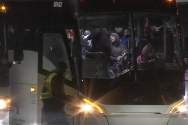 Migrants board a bus as they arrived on a plane from San Antonio at Chicago Rockford International Airport at 1am on Jan. 1, 2024 in Rockford, Ill. The city of Chicago said 355 migrants on the Boeing 777 boarded eight buses chartered by Abbott to be dropped off in "various suburbs." (WTVO NewsNation via AP)