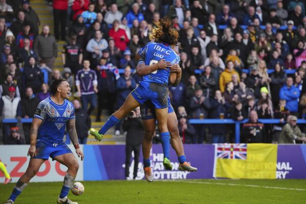 Samoa's players celebrate with teammate Brian To'o after scoring a try during the Rugby League World Cup quarter-final match between Tonga and Samoa at The Halliwell Jones Stadium in Warrington, England, Sunday, Nov. 6, 2022. (AP Photo/Jon Super)