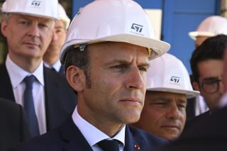 FILE - French President Emmanuel Macron and Finance Minister Bruno Le Maire, left, listen to explanations as they visit the STMicroelectronics (STM) company in Crolles, southeastern France, Tuesday July 12, 2022. The French government forecasts growth to slow down substantially next year in the EU's second biggest economy, amid fears of recession in neighboring Germany as the economic situation in Europe is aggravated bythe consequences of Russia's war in Ukraine. (Jean-Philippe Ksiazek, pool via AP)