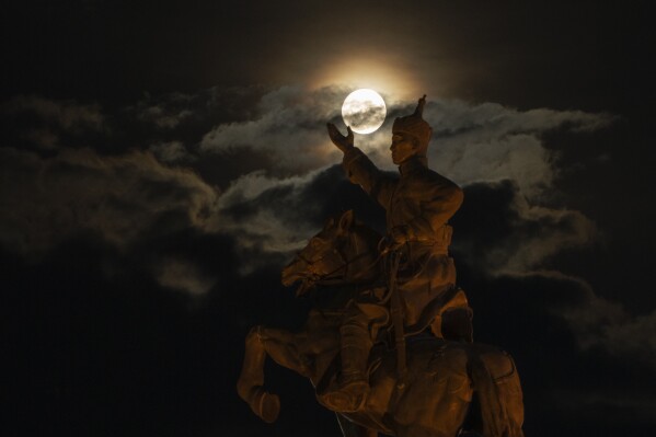 The supermoon rises near the equestrian statue of Damdin Sukhbaatar on Sukhbaatar Square in Ulaanbaatar, Mongolia, on Wednesday, Aug. 30, 2023. (AP Photo/Ng Han Guan)