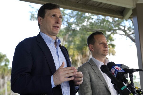 U.S. Rep. Daniel Goldman, D-N.Y., left, speaks with the news media before a tour of Marjory Stoneman Douglas High School, Monday, Nov. 20, 2023, in Parkland, Fla. Fourteen students and three staff members were fatally shot at the school in 2018. At right is Rep. Jared Moskowitz, D-Fla., right. (AP Photo/Lynne Sladky)