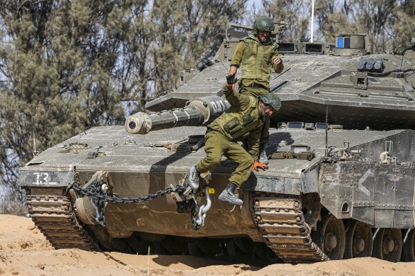 Israeli soldiers jump off a tank at a staging ground near the border with the Gaza Strip, in southern Israel, Sunday, May 5, 2024. (AP Photo/Tsafrir Abayov)