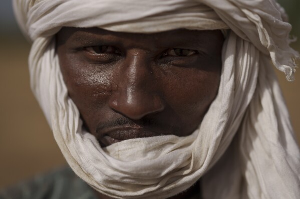 Moussa Ifra Ba, stands for a portrait in the village of Dendoudy Dow, in the Matam region of Senegal, Monday, April 17, 2023. The 28-year-old herder can't imagine any other life. "A village without cows has no soul. ... I love pastoralism to the core". The father of a two-year-old girl, he travels with his wife and her family taking care of the sheep and cows. "If I'm lucky enough to have three boys, I'd like two of them to go to school and the third to take over from me", he says. (AP Photo/Leo Correa)