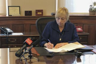 Maine Democratic Gov. Janet Mills signs a bill Wednesday, June 12, 2019, in her office in Augusta, Maine, becoming the eighth state to allow terminally ill people to end their lives with prescribed medication. (AP Photo/Marina Villeneuve)