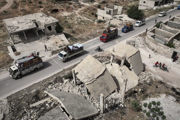 Trucks and vans carrying around 60 displaced families arrive in their village after more than five years in the Atmeh camps near the Syrian-Turkish border, in Kafr Sijna, south of Idlib, Syria, Sunday, May 18, 2025. (AP Photo/Ghaith Alsayed)