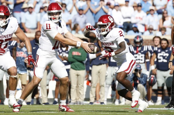 Oklahoma quarterback Jackson Arnold (11) hands off the ball to running back Jovantae Barnes (2) during the first half of an NCAA college football game against Mississippi, Saturday, Oct. 26, 2024, in Oxford, Miss. (AP Photo/Sarah Warnock)