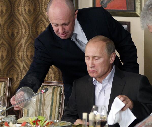 FILE - Yevgeny Prigozhin, top, serves food to then-Russian Prime Minister Vladimir Putin at Prigozhin's restaurant outside Moscow, Russia in Nov. 11, 2011. Kremlin-connected businessman Yevgeny Prigozhin kept a low profile over the years, but he has been increasingly in the spotlight recently. He has admitted that he is behind the Russian mercenary force that reportedly has been involved in conflicts around the world, including Ukraine. (AP Photo/Misha Japaridze, Pool, File)