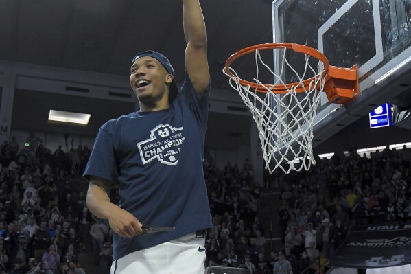 Utah State guard Darius Brown II holds up a piece of the net after the team's win over New Mexico in an NCAA college basketball game Saturday, March 9, 2024, in Logan, Utah. The victory clinched the Mountain West Conference regular-season championship for Utah State. (Eli Lucero/The Herald Journal via AP)