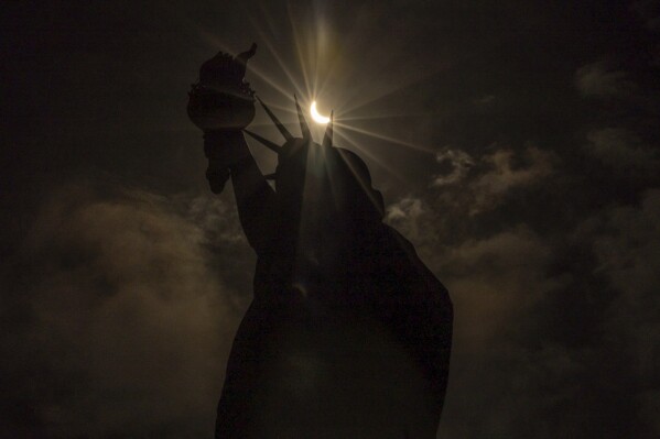 The moon partially covers the sun behind the Statue of Liberty during the a solar eclipse on the Liberty Island, Monday, April 8, 2024, in New York. (AP Photo/Yuki Iwamura)