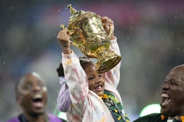 A girl lifts the trophy next to South Africa's Mbongeni Mbonambi after the Rugby World Cup final match between New Zealand and South Africa at the Stade de France in Saint-Denis, near Paris Saturday, Oct. 28, 2023. South Africa won 12-11. (AP Photo/Pavel Golovkin)