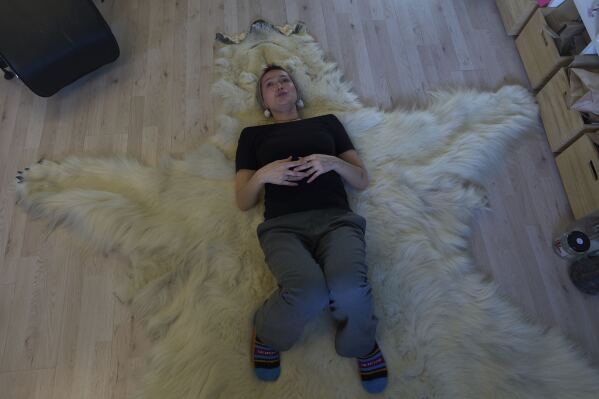 Shaman Aviaja Rakel Sanimuinaq lies on the pelt of a polar bear her family hunted and is now kept in a studio where she performs Inuit ancestral spiritual healing in Nuuk, Greenland, on Wednesday, Feb. 19, 2025. (AP Photo/Luis Andres Henao)