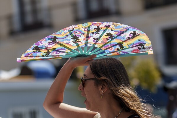 ARCHIVO - Una mujer se protege del sol con un ventilador portátil en Madrid, España, 10 de julio de 2023. Los últimos cálculos de varias agencias científicas, el viernes 12 de enero de 2024, indican que las temperaturas medias globales para 2023 batieron los récords de calor existentes.  (Foto AP/Manu Fernández, Archivo)