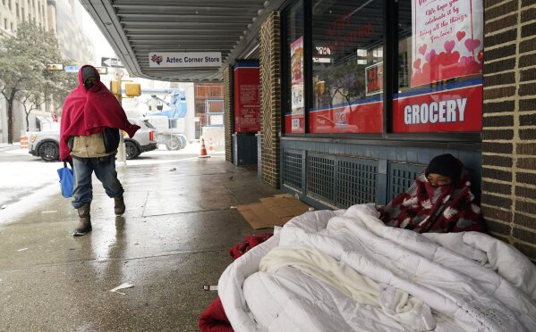 A woman living on the streets uses blankets to keep warm, Thursday, Feb. 18, 2021, in downtown San Antonio. Snow, ice and sub-freezing weather continue to wreak havoc on the state's power grid and utilities. (AP Photo/Eric Gay)