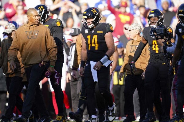 Washington Commanders quarterback Sam Howell (14) walks back to the team bench near the end of the first half of an NFL football game against the New York Giants, Sunday, Nov. 19, 2023, in Landover, Md. (AP Photo/Stephanie Scarbrough)