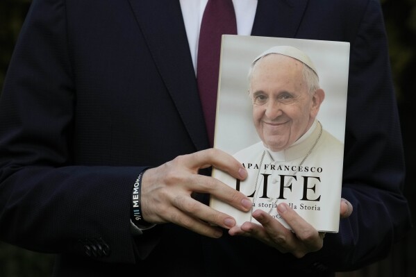 Italian journalist and writer Fabio Marchese Ragona holds a copy of "Life: My Story Through History" as he poses for a picture prior to the start of an interview with the Associated Press, in Rome, Thursday, March 13, 2024. Pope Francis says he has no plans to resign and isn't suffering from any health problems that would require doing so, in an autobiography, "Life: My Story Through History," which is being published Tuesday and written with Italian journalist Fabio Marchese Ragona. (AP Photo/Gregorio Borgia)