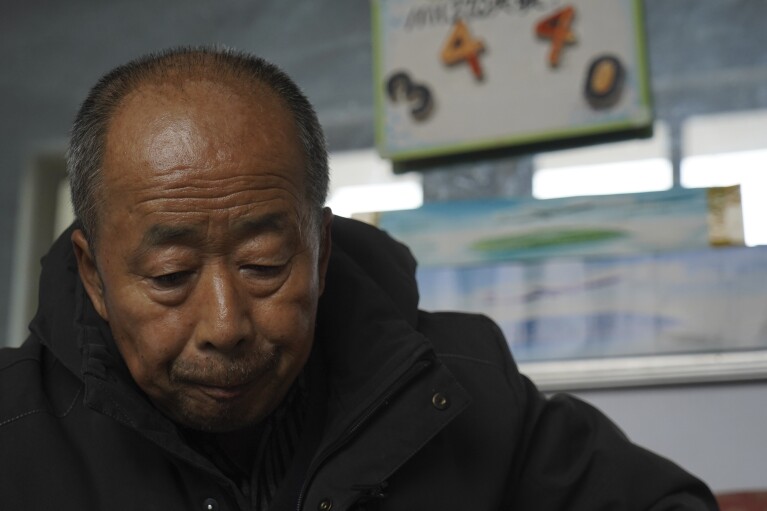 Chinese farmer Li Eryou, whose son Li Yanlin was on the missing Malaysia Airlines flight MH370, pauses near a board he had used to count the days after the plane went missing at a village in Handan in northern China's Hebei province on Feb. 28, 2024. The baffling disappearance of flight MH370 still captivates people around the world. The Boeing 777 left Kuala Lumpur with 239 people on March 8, 2014, but dropped off radar screens shortly after and never made it to Beijing, its destination. Investigators say someone deliberately shut down the plane's communications system and took the plane off course. (AP Photo/Emily Wang Fujiyama)