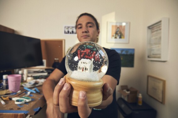Jesse McLaren holds one of his custom-built snow globes in Los Angeles on Sept. 6, 2023. McLaren, who writes for “Jimmy Kimmel Live!” decided to monetize his hobby of making snow globes when members of the Writers Guild of America went on strike. (Matt Martin via AP)