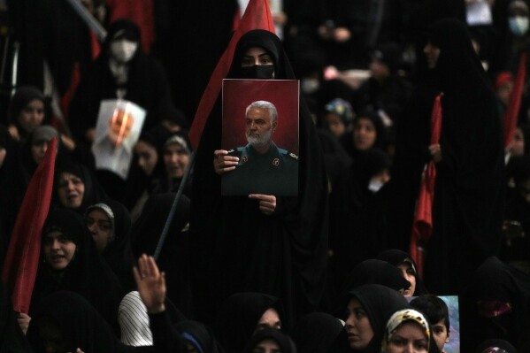 A woman holds up a poster of the late Revolutionary Guard Gen. Qassem Soleimani, who was killed in a U.S. drone attack in 2020 in Iraq, during a commemoration for him at the Imam Khomeini grand mosque in Tehran, Iran, Wednesday, Jan. 3, 2024. Two bombs exploded Wednesday at a commemoration for a prominent Iranian general slain by the U.S. in a 2020 drone strike, Iranian officials said, as the Middle East remains on edge over Israel's war on Hamas in the Gaza Strip. (AP Photo/Vahid Salemi)