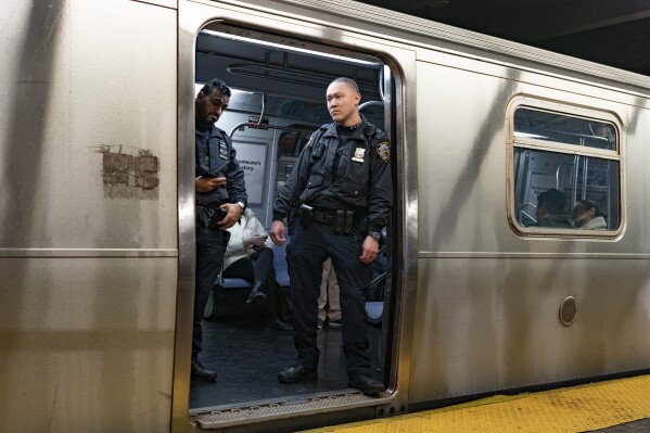 FILE - NYPD officers stand aboard a train at the West Fourth Street subway station, Saturday, Jan. 13, 2024, in New York. Prosecutors say a man who shot and critically wounded another man on a New York City subway train will not immediately be charged with a crime while prosecutors investigate whether the shooter acted justifiably in self-defense.(AP Photo/Peter K. Afriyie, File)