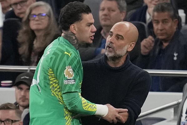 Manchester City's goalkeeper Ederson is substituted and speaks to Manchester City's head coach Pep Guardiola during the English Premier League soccer match between Tottenham Hotspur and Manchester City at Tottenham Hotspur Stadium in London, Tuesday, May 14, 2024.(AP Photo/Kin Cheung)