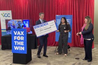 Gov. Gavin Newsom presents a check to Nancy Gutierrez, the winner of $50K lottery for getting vaccinated as Assemblywoman Tasha Boerner Horvath, right looks on in San Diego, Calif. on Friday, June 11, 2021. (AP Photo/Elliot Spagat)