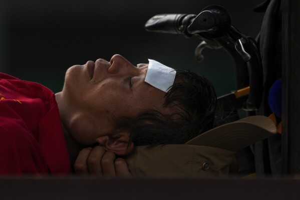 FILE - A man with a cooling pad on his forehead takes a nap on a bench on a sweltering day in Beijing, July 24, 2023. At about summer's halfway point, the record-breaking heat and weather extremes are both unprecedented and unsurprising, hellish yet boring in some ways, scientists say. (AP Photo/Andy Wong, File)