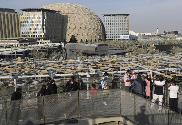 FILE - People take photos of the Al Wasl dome from the South Korea Pavilion during the UAE 50th National Day at EXPO 2020 Dubai, in Dubai, United Arab Emirates, Dec. 2, 2021. Dubai's Expo City, built for $7 billion for its 2020 world fair delayed a year by the coronavirus pandemic, will host the upcoming climate talks. (AP Photo/Kamran Jebreili, File)
