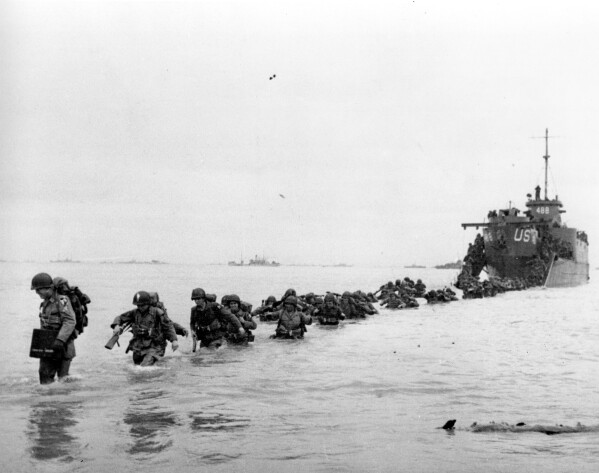 FILE - U.S. reinforcements wade through the surf from a landing craft in the days following D-Day and the Allied invasion of Nazi-occupied France at Normandy in June 1944 during World War II. France is getting ready to show its gratitude towards World War II veterans who will come, many for the last time, on Normandy beaches for D-Day ceremonies that will come as part of a series of major commemorations this year and next marking eight decades since the defeat of the Nazis. (Bert Brandt/Pool via AP, File)