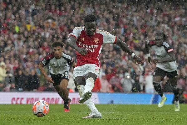 Arsenal's Bukayo Saka shoots to score his side's first goal during the English Premier League soccer match between Arsenal and Fulham at Emirates stadium in London, Saturday, Aug. 26, 2023. (AP Photo/Frank Augstein)