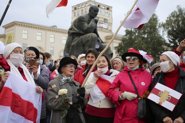 Opposition activist Nina Bahinskaya, 73, center left, holds an old Belarusian national flag during an opposition rally to protest the official presidential election results in Minsk, Russia, Monday, Oct. 26, 2020. (AP Photo, File)