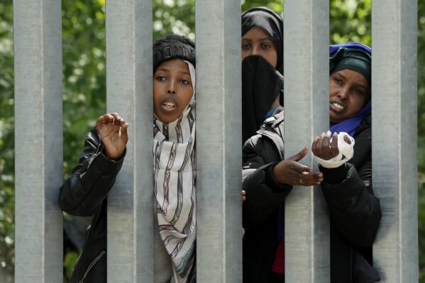 A view of migrants behind the metal barrier border that Poland has erected along the border with Belarus, in Bialowieza Forest, on Wednesday, May 29, 2024. Poland says neighboring Belarus and its main supporter Russia are behind a surging push by migrants in Belarus toward the European Union. (AP Photo/Czarek Sokolowski)
