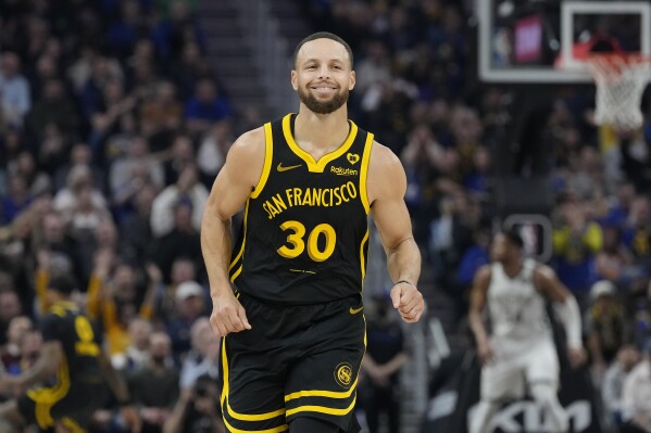 Golden State Warriors guard Stephen Curry smiles after making a 3-point basket against the Milwaukee Bucks during the first half of an NBA basketball game in San Francisco, Wednesday, March 6, 2024. (AP Photo/Jeff Chiu)