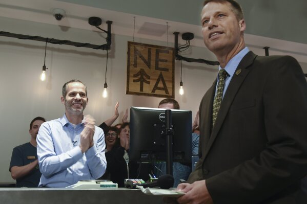 
              Arnon Vered, co-founder of NETA sells the first edible marijuana candy bar to Mayor David Narkewicz at 8:00 am while a line developed around NETA in Northampton of people who had gotten there as early as 12:30 am waited for NETA to open to legally buy recreational marijuana Tuesday, Nov. 20, 2018.(Carol Lollis/The Daily Hampshire Gazette via AP)
            