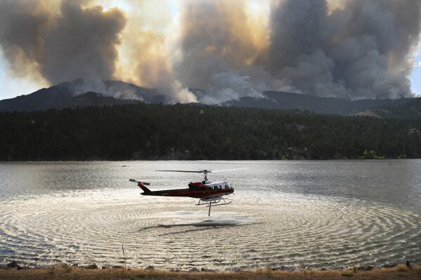 A helicopter collects water to drop on the Alexander Mountain Fire burning Monday, July 29, 2024, west of Loveland, Colo. (Helen H. Richardson/The Denver Post via AP)