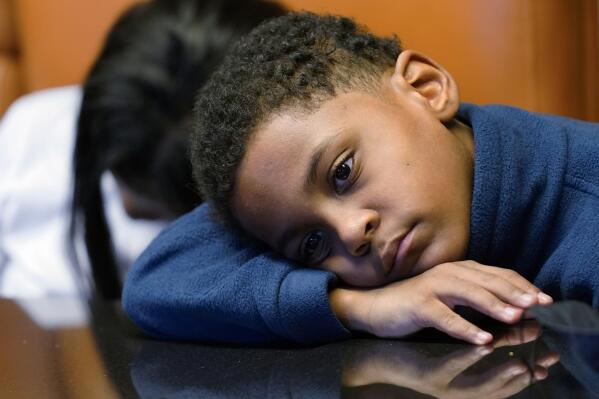 In this Sept. 23, 2021, photo Jhaimarion, 10, reacts as he listens to his mother, Krystal Archie talking with an Associated Press reporter in Chicago. Archie’s three children were present when police, on two occasions, just 11 weeks apart, kicked open her front door and tore through their home searching for drug suspects. She’d never heard of the people they were hunting. Her oldest child, Savannah was 14 at the time; her youngest, Jhaimarion, was seven. They were ordered to get down on the floor.  (AP Photo/Nam Y. Huh)