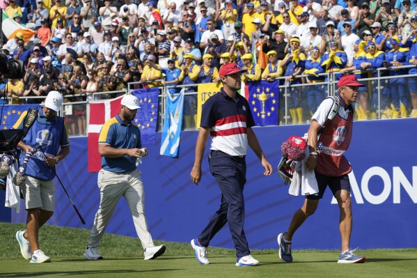 United States' Scottie Scheffler, second right, and Europe's Jon Rahm second left, walk off the 1st tee during their singles match at the Ryder Cup golf tournament at the Marco Simone Golf Club in Guidonia Montecelio, Italy, Sunday, Oct. 1, 2023. (AP Photo/Alessandra Tarantino)