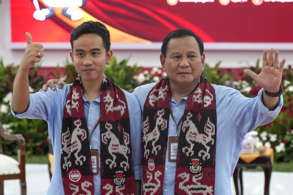 FILE - Presidential candidate Prabowo Subianto, right, and his running mate Gibran Rakabuming Raka, the eldest son of President Joko Widodo, wave at the media after registering their candidacy to run in the 2024 election, at the General Election Commission building in Jakarta, Indonesia, on Oct. 25, 2023. Indonesia's Election Commission announced Monday Nov. 13, 2023 that it has approved all three presidential candidates for next February's election, including a former special forces general whose vice presidential running mate is the son of outgoing President Joko Widodo. (AP Photo/Tatan Syuflana, File)