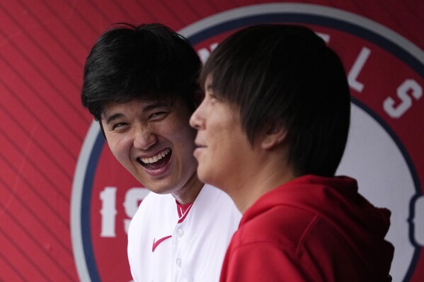 Los Angeles Angels' Shohei Ohtani, left, laughs as he talks to his interpreter Ippei Mizuhara prior to a baseball game against the Pittsburgh Pirates, Sunday, July 23, 2023, in Anaheim, Calif. (AP Photo/Mark J. Terrill)