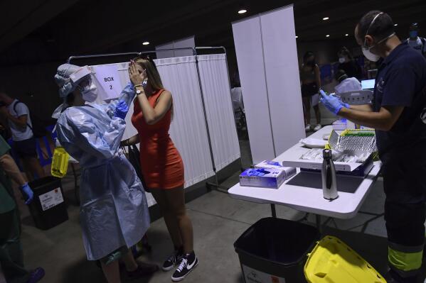 A health worker takes a swab from a teenager during a rapid antigen test for COVID-19 in Pamplona, northern Spain, Monday, July 5, 2021. During the last three days local authorities have called on teenagers to be tested due to the increase of people in the town contracting coronavirus after returning from vacations in the small village of Salou, northeast of Spain. (AP Photo/Alvaro Barrientos)