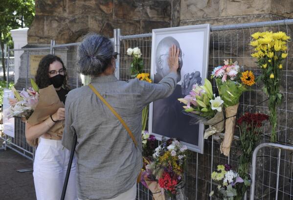 People place flowers alongside a photo of Anglican Archbishop Desmond Tutu at the St. George's Cathedral in Cape Town, South Africa, Sunday, Dec. 26, 2021. South Africa's president says Tutu, South Africa's Nobel Peace Prize-winning activist for racial justice and LGBT rights and the retired Anglican Archbishop of Cape Town, has died at the age of 90. (AP Photo)