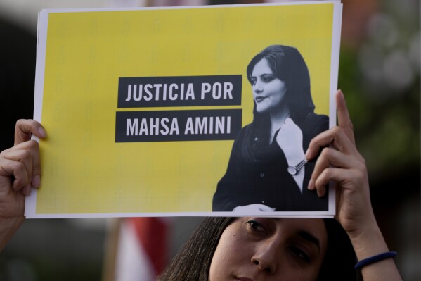 FILE - A woman holds a sign that reads in Spanish 