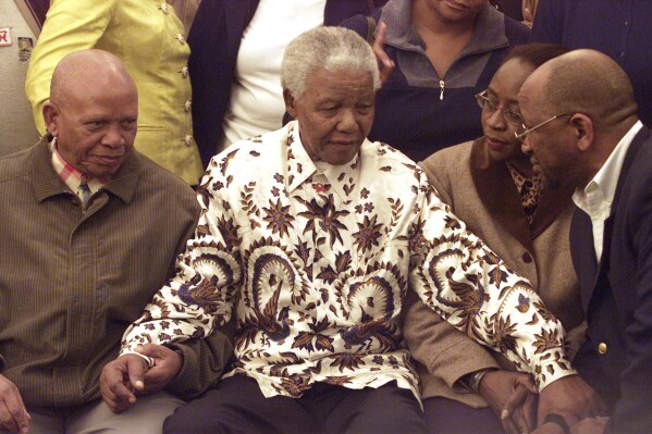FILE - Former South African President Nelson Mandela, centre, wears a printed shirt in Johannesburg, on July 18, 2003 as part of his 85th birthday celebrations. The planned auction of dozens of artifacts belonging to Nelson Mandela has been suspended pending a court application to completely halt it, the body that protects South Africa's cultural heritage said Tuesday, Jan. 30, 2024. (AP Photo/Themba Hadebe, File)