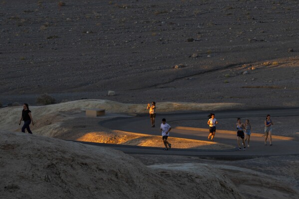 People run to get sunset photos at Zabriskie Point on Saturday, July 8, 2023, in Death Valley National Park, Calif. July is the hottest month at the park with an average high of 116 degrees (46.5 Celsius). (AP Photo/Ty ONeil)